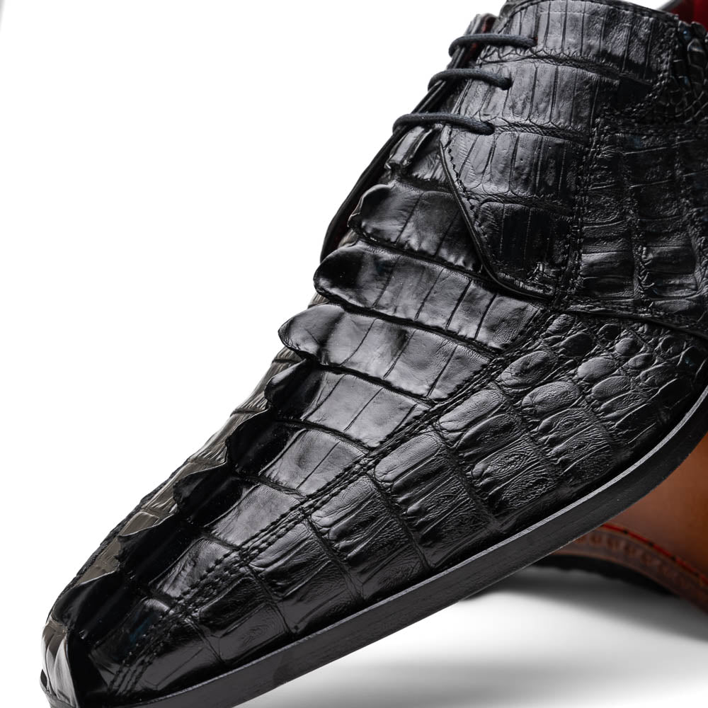 The Marco Di Milano Cancun Black features genuine hornback caiman crocodile shoes with a pointed toe, one upright and the other showing the branded brown leather sole—a striking choice in men's exotic footwear.