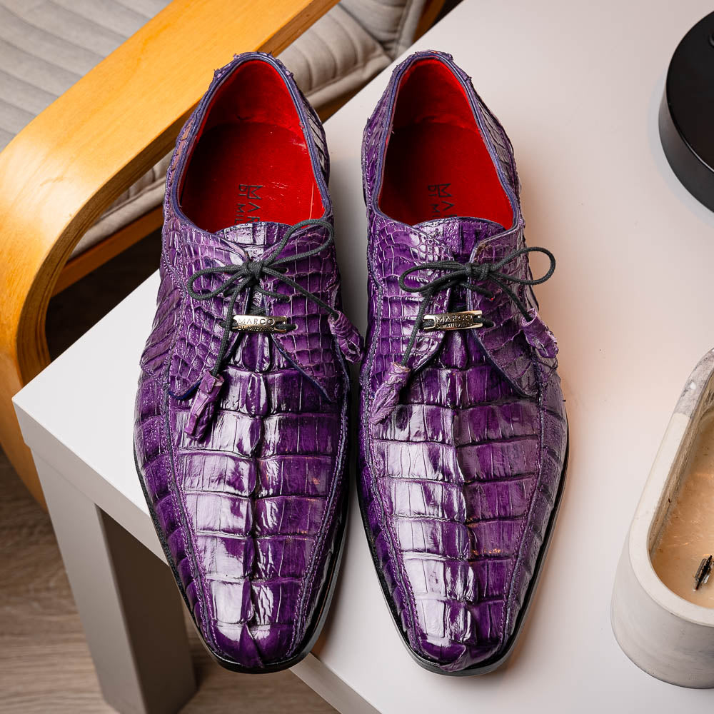 The Marco Di Milano Cancun Purple is a luxurious pair of derby shoes crafted from genuine hornback caiman crocodile leather, hand-painted in purple with black laces—one shown upright, the other displaying a tan branded sole.