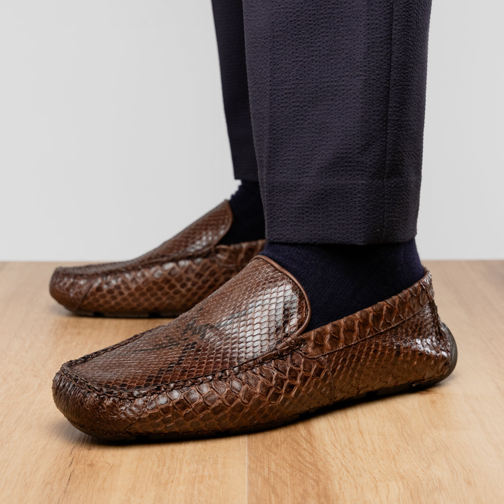 A pair of Capri Brown luxury exotic shoes by Marco Di Milano, crafted from genuine python leather, with one handcrafted men’s loafer standing upright and the other displayed on its side to highlight the intricately textured sole.