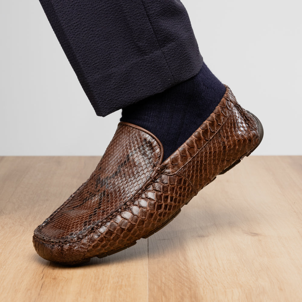 A pair of Capri Brown luxury exotic shoes by Marco Di Milano, crafted from genuine python leather, with one handcrafted men’s loafer standing upright and the other displayed on its side to highlight the intricately textured sole.