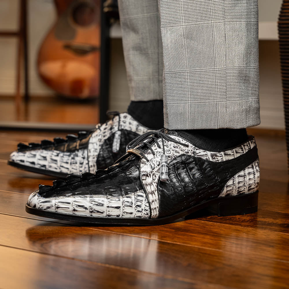The Marco Di Milano Caribe Black / Newspaper are luxury men's derby shoes crafted from genuine hornback caiman crocodile leather in black and white, featuring red lining, leather soles, lace-up closures, and decorative tassels.