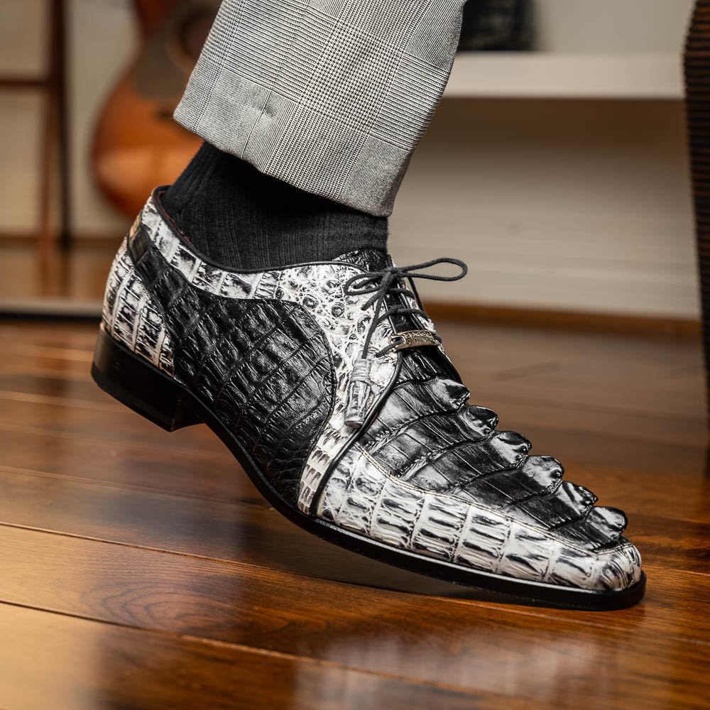 The Marco Di Milano Caribe Black / Newspaper are luxury men's derby shoes crafted from genuine hornback caiman crocodile leather in black and white, featuring red lining, leather soles, lace-up closures, and decorative tassels.