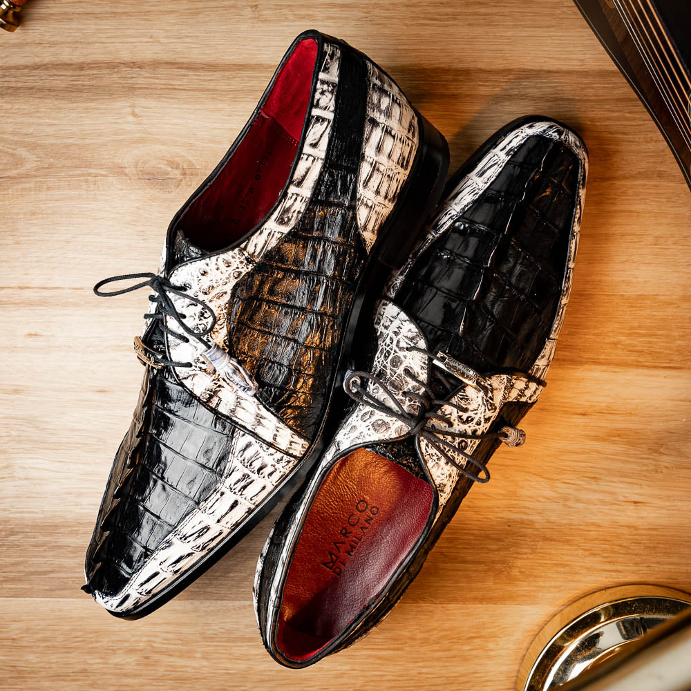The Marco Di Milano Caribe Black / Newspaper are luxury men's derby shoes crafted from genuine hornback caiman crocodile leather in black and white, featuring red lining, leather soles, lace-up closures, and decorative tassels.