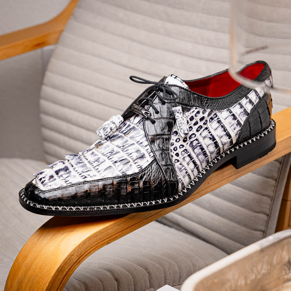 A pair of Marco Di Milano Caribe Newspaper / Black luxury dress shoes crafted from genuine hornback caiman crocodile leather, with one upright and the other on its side showing the brown sole and exquisite hand-painted details.