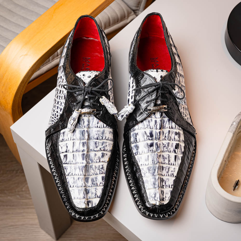 A pair of Marco Di Milano Caribe Newspaper / Black luxury dress shoes crafted from genuine hornback caiman crocodile leather, with one upright and the other on its side showing the brown sole and exquisite hand-painted details.