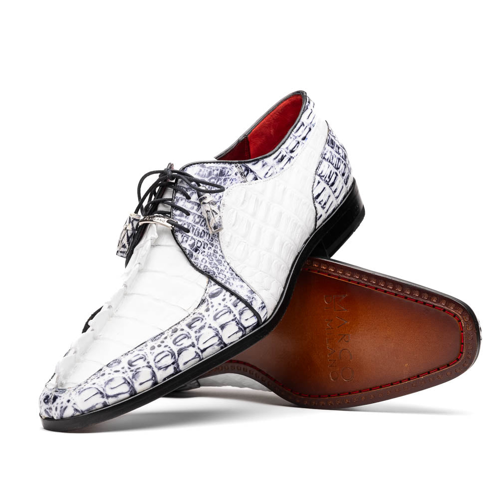 The Marco Di Milano Caribe White / Newspaper Derby shoes feature white and black crocodile-patterned leather, one upright and one on its side to showcase a brown leather sole with red stitching—distinctive, exotic hand-painted footwear.