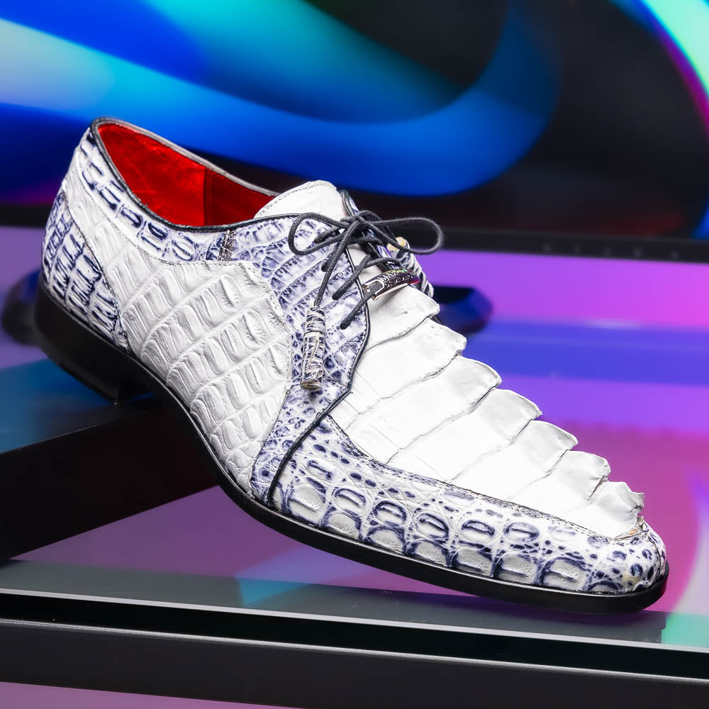 The Marco Di Milano Caribe White / Newspaper Derby shoes feature white and black crocodile-patterned leather, one upright and one on its side to showcase a brown leather sole with red stitching—distinctive, exotic hand-painted footwear.