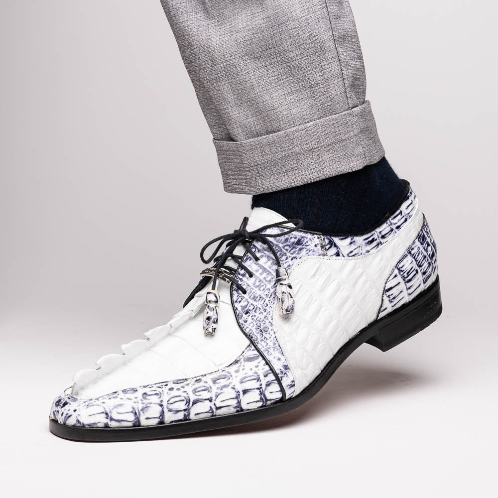 The Marco Di Milano Caribe White / Newspaper Derby shoes feature white and black crocodile-patterned leather, one upright and one on its side to showcase a brown leather sole with red stitching—distinctive, exotic hand-painted footwear.