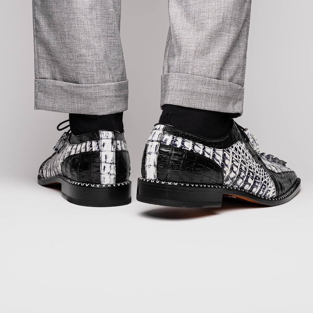 A pair of Marco Di Milano Caribe Newspaper / Black luxury dress shoes crafted from genuine hornback caiman crocodile leather, with one upright and the other on its side showing the brown sole and exquisite hand-painted details.