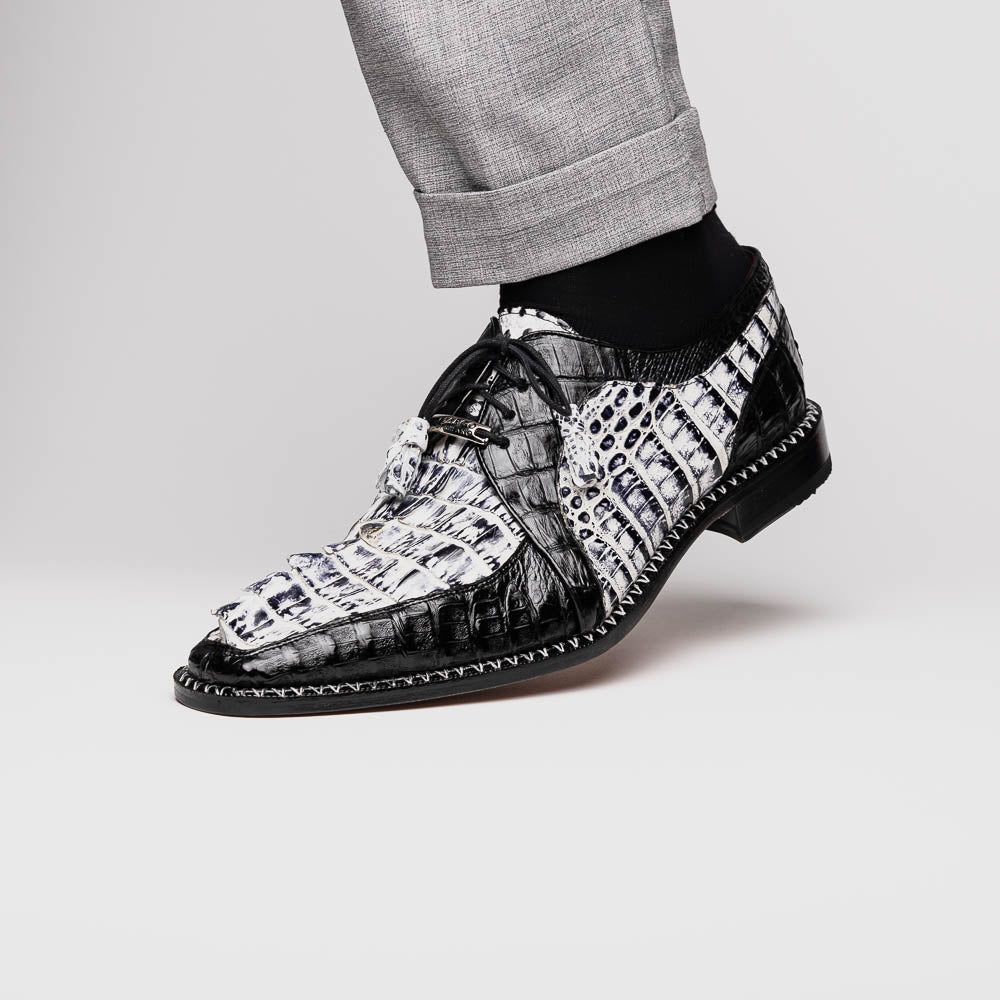 A pair of Marco Di Milano Caribe Newspaper / Black luxury dress shoes crafted from genuine hornback caiman crocodile leather, with one upright and the other on its side showing the brown sole and exquisite hand-painted details.