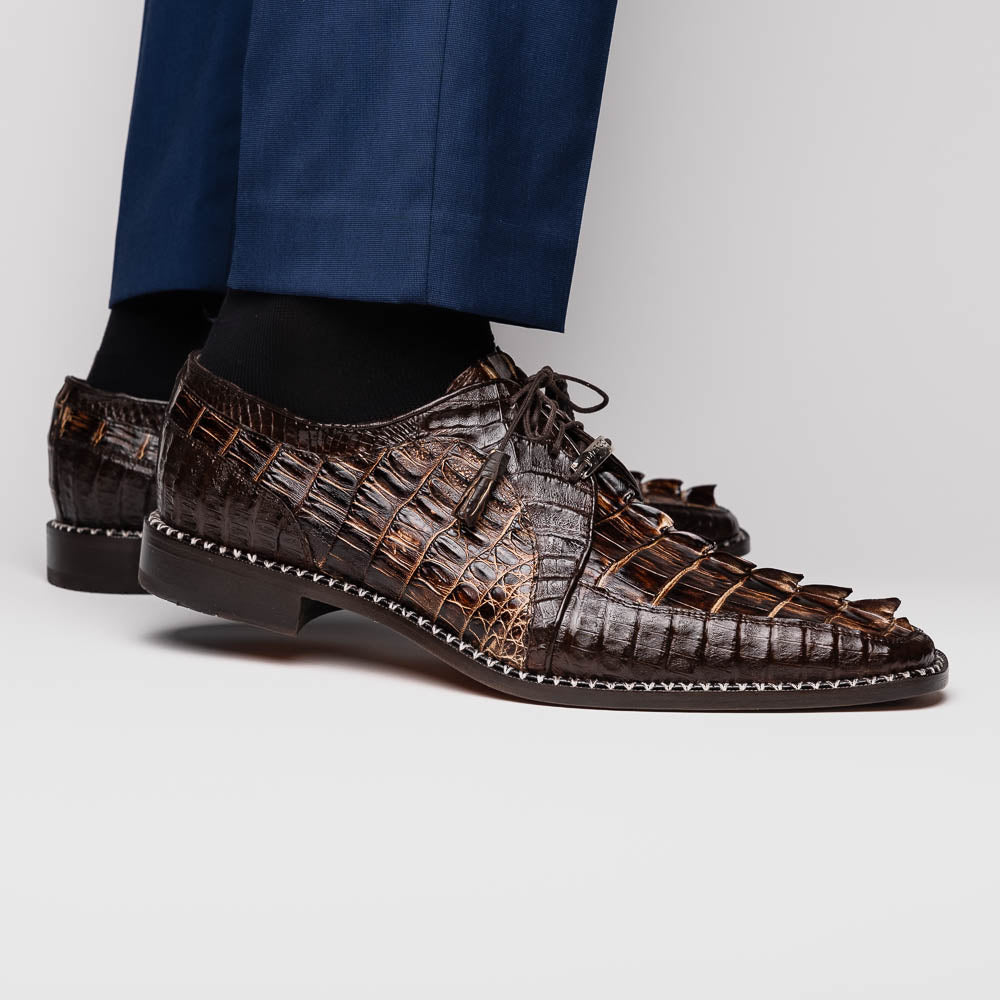 The Marco Di Milano Caribe Rustic Orix/Brown features luxury derby shoes crafted from genuine hornback caiman crocodile leather, with one upright and the other on its side showcasing a tan sole, visible stitching, and hand-painted finishes.