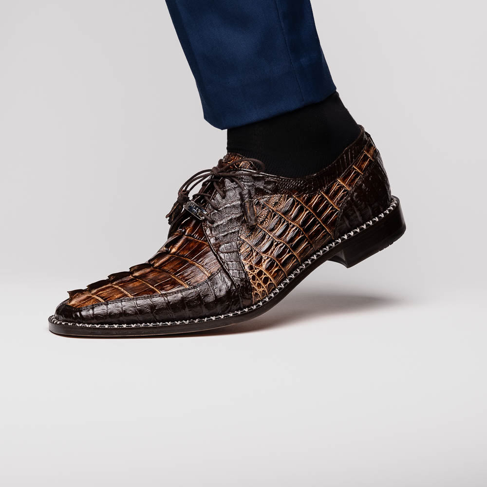 The Marco Di Milano Caribe Rustic Orix/Brown features luxury derby shoes crafted from genuine hornback caiman crocodile leather, with one upright and the other on its side showcasing a tan sole, visible stitching, and hand-painted finishes.