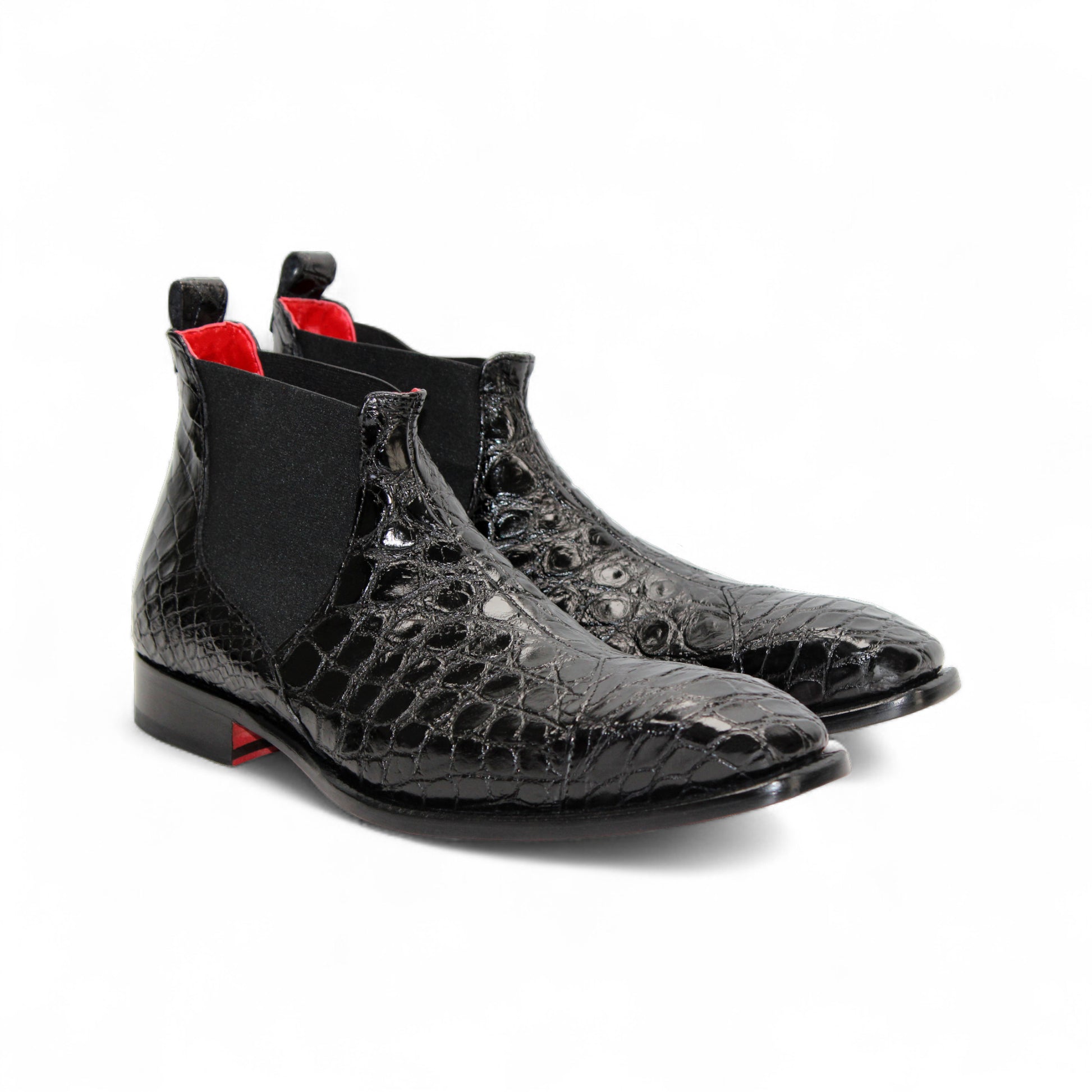 The Fennix Cole Black by Fennix of Italy is a luxury Chelsea boot in genuine alligator leather with a crocodile pattern, elastic side panel, low heel, and bold red sole accent—elegantly displayed in profile.