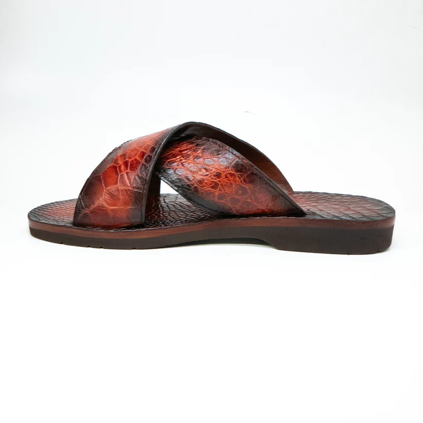 The Elios Cognac sandal by Marco Di Milano features brown textured crossing straps, a flat sole, luxury materials, and hand-painted finishes, all showcased on a white background.