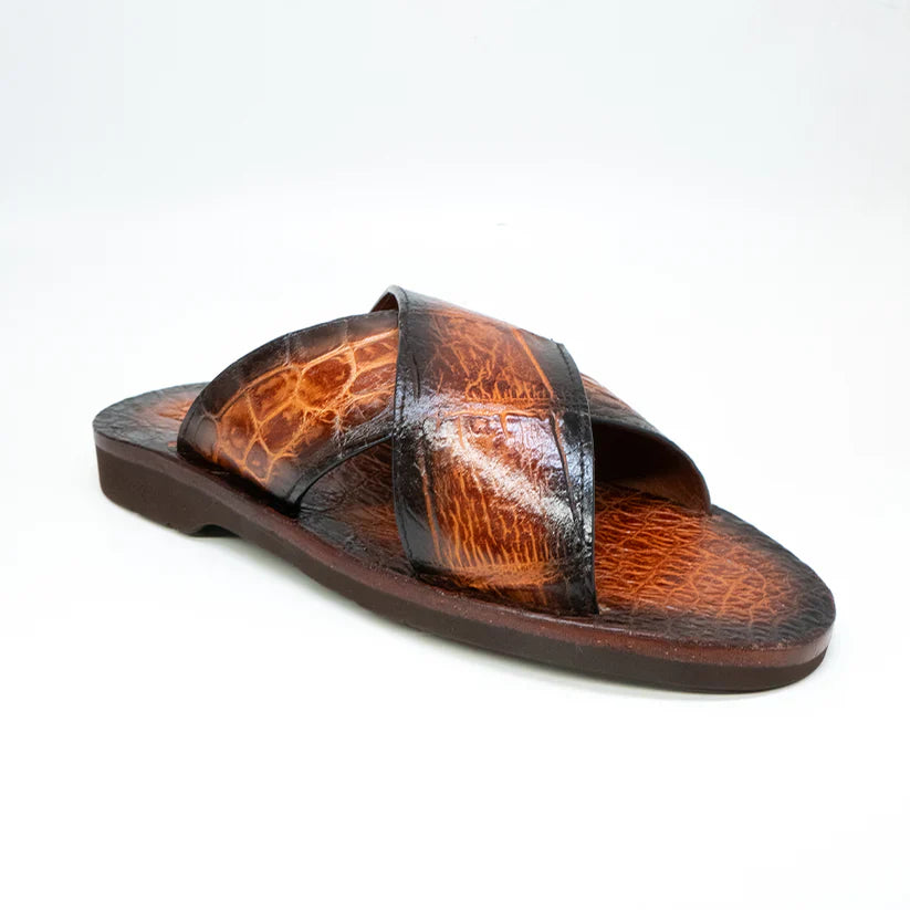 The Elios Honey by Marco Di Milano is a luxury brown leather sandal with a crocodile-textured finish and two crisscross straps, hand painted for elegance and showcased on a white background.