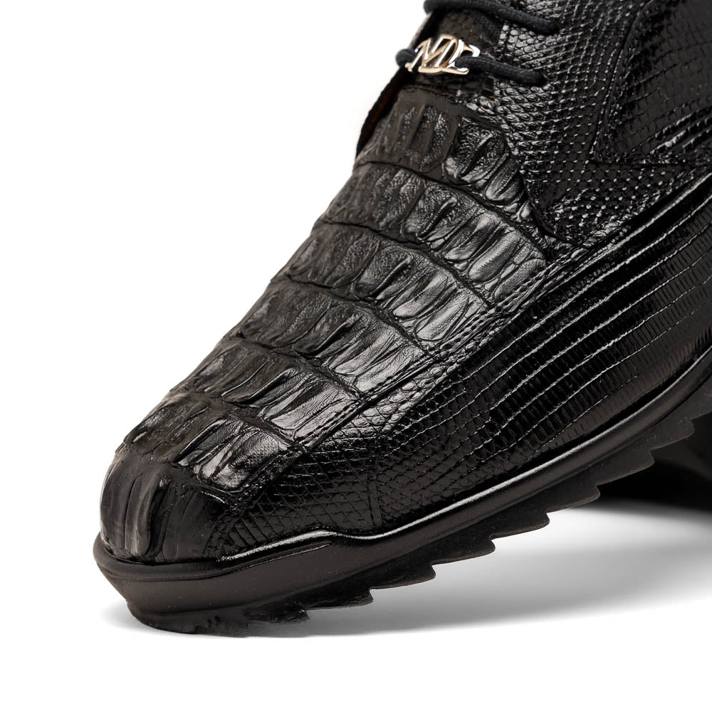 The Crater Black by Marco Di Milano features black textured leather with a crocodile pattern and metallic logo accents, exemplifying genuine exotic shoe craftsmanship—one shoe stands upright, the other lies on its side.