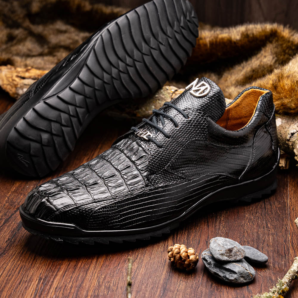 The Crater Black by Marco Di Milano features black textured leather with a crocodile pattern and metallic logo accents, exemplifying genuine exotic shoe craftsmanship—one shoe stands upright, the other lies on its side.