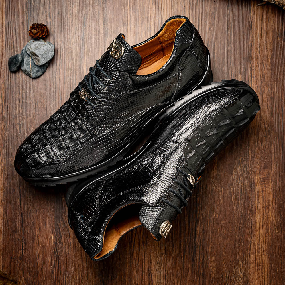 The Crater Black by Marco Di Milano features black textured leather with a crocodile pattern and metallic logo accents, exemplifying genuine exotic shoe craftsmanship—one shoe stands upright, the other lies on its side.