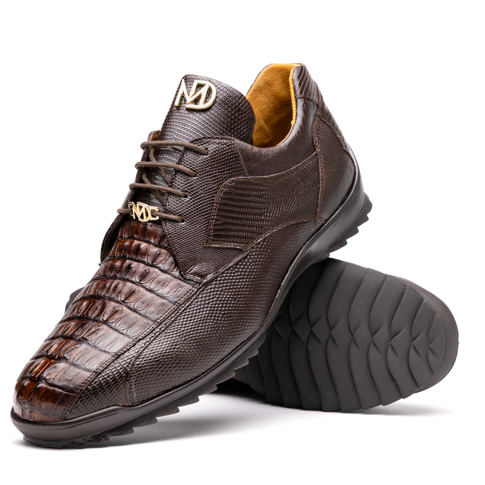 The Crater Brown by Marco Di Milano features brown textured leather with crocodile pattern accents, gold "MD" logos, and black rubber soles, blending dress shoe elegance with caiman hornback sneaker style.