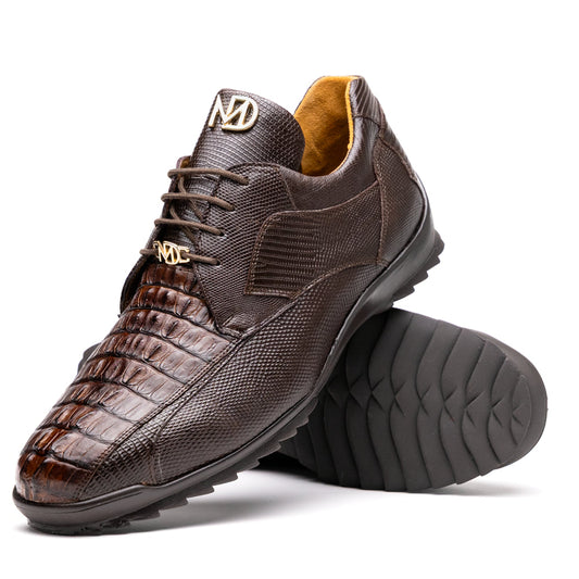The Crater Brown by Marco Di Milano features brown textured leather with crocodile pattern accents, gold "MD" logos, and black rubber soles, blending dress shoe elegance with caiman hornback sneaker style.