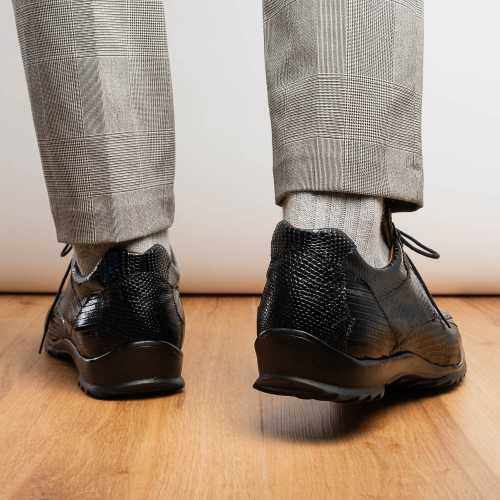 The Crater Black by Marco Di Milano features black textured leather with a crocodile pattern and metallic logo accents, exemplifying genuine exotic shoe craftsmanship—one shoe stands upright, the other lies on its side.