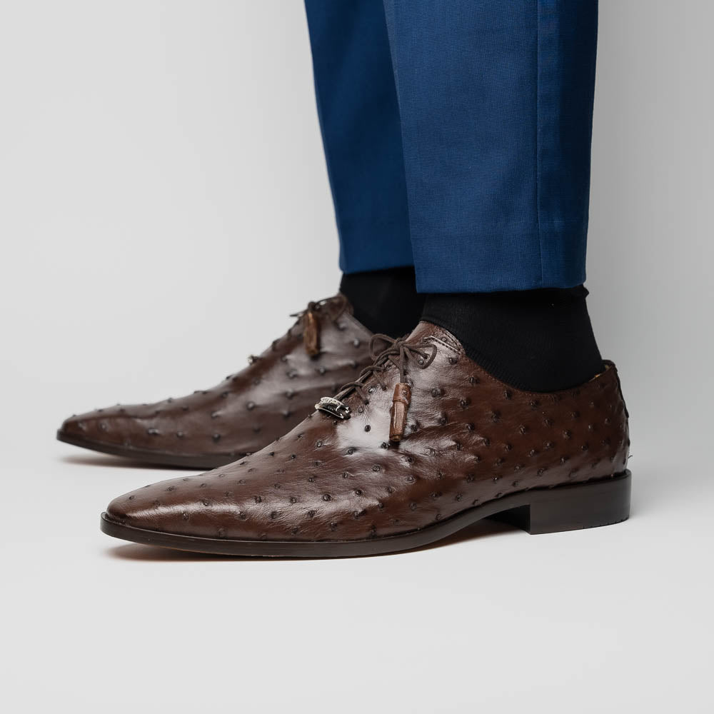 The Criss Brown by Marco Di Milano is a pair of luxury dress oxfords in dark brown genuine ostrich quill leather with decorative laces and a leather sole, shown with one shoe elegantly displayed on its side atop the other.