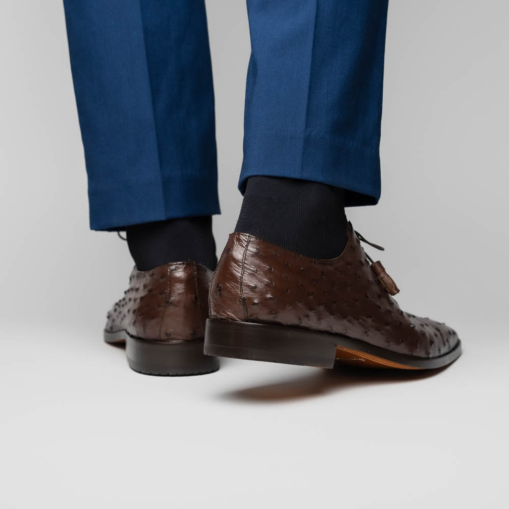 The Criss Brown by Marco Di Milano is a pair of luxury dress oxfords in dark brown genuine ostrich quill leather with decorative laces and a leather sole, shown with one shoe elegantly displayed on its side atop the other.