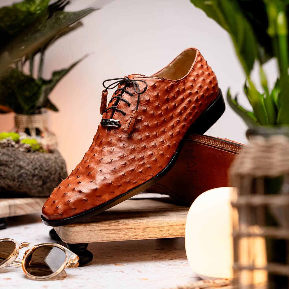 A pair of Criss Brandy genuine ostrich quill leather luxury dress oxfords by Marco Di Milano, with one shoe upright and the other sole up to display the brand name.