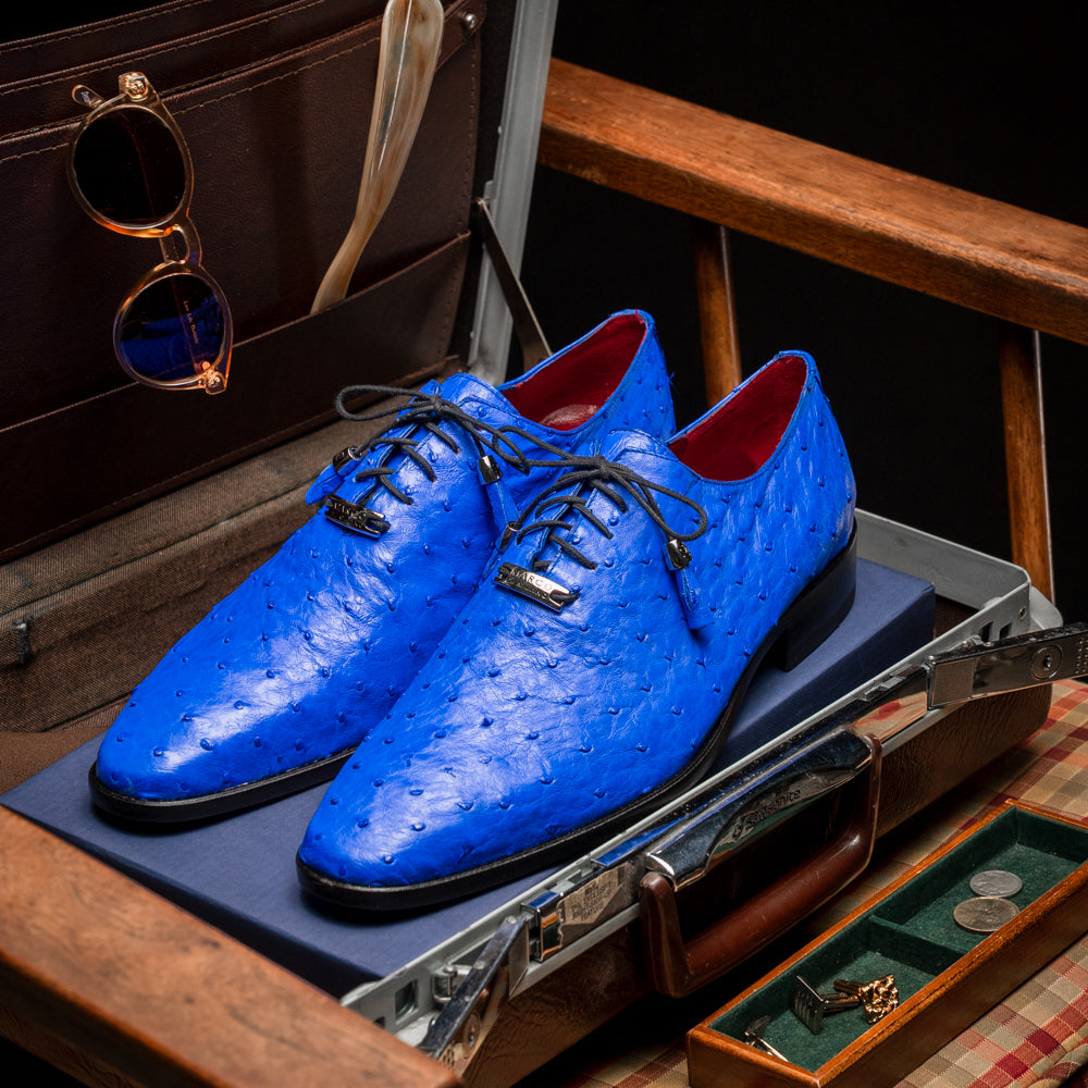 Introducing the Criss Electric Blue by Marco Di Milano—a pair of vibrant blue genuine ostrich quill leather oxford dress shoes featuring stylish laces and sleek metal detailing. One shoe stands upright while the other displays its beautifully crafted sole, making them an exceptional choice for anyone looking for distinctive luxury footwear.