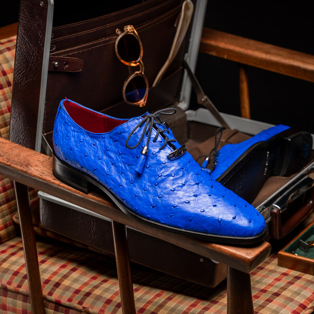 Introducing the Criss Electric Blue by Marco Di Milano—a pair of vibrant blue genuine ostrich quill leather oxford dress shoes featuring stylish laces and sleek metal detailing. One shoe stands upright while the other displays its beautifully crafted sole, making them an exceptional choice for anyone looking for distinctive luxury footwear.