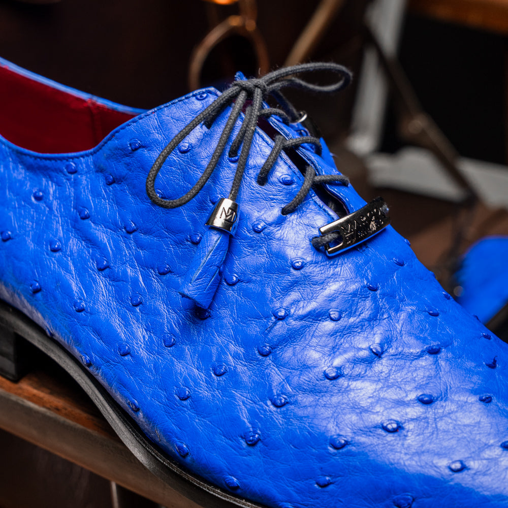 Introducing the Criss Electric Blue by Marco Di Milano—a pair of vibrant blue genuine ostrich quill leather oxford dress shoes featuring stylish laces and sleek metal detailing. One shoe stands upright while the other displays its beautifully crafted sole, making them an exceptional choice for anyone looking for distinctive luxury footwear.