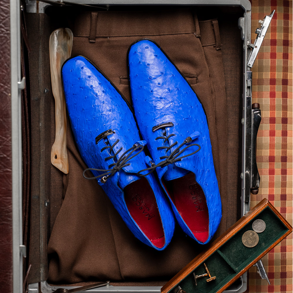 Introducing the Criss Electric Blue by Marco Di Milano—a pair of vibrant blue genuine ostrich quill leather oxford dress shoes featuring stylish laces and sleek metal detailing. One shoe stands upright while the other displays its beautifully crafted sole, making them an exceptional choice for anyone looking for distinctive luxury footwear.