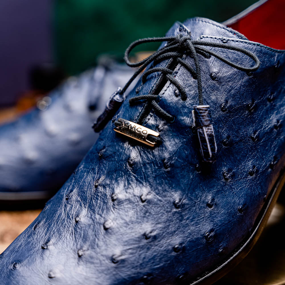 The Criss Navy by Marco Di Milano: a pair of genuine ostrich dress shoes with blue leather, black laces, red inner lining, and brown soles—one upright, one on its side—showcasing luxury men’s footwear.