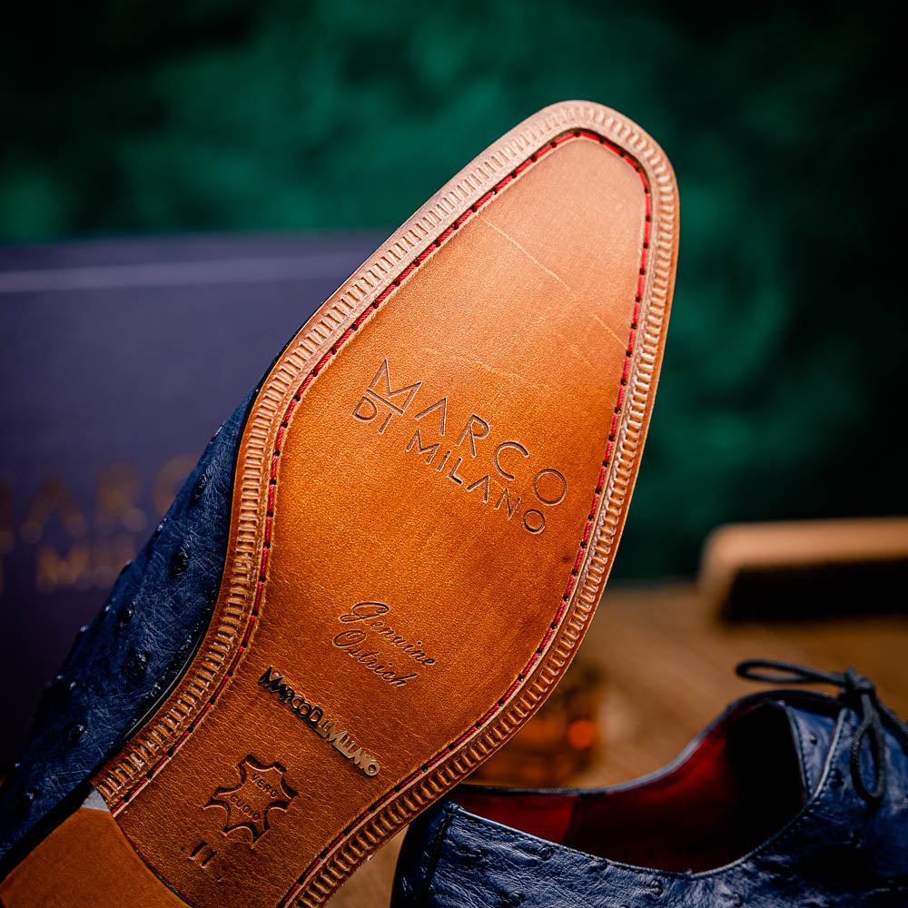 The Criss Navy by Marco Di Milano: a pair of genuine ostrich dress shoes with blue leather, black laces, red inner lining, and brown soles—one upright, one on its side—showcasing luxury men’s footwear.
