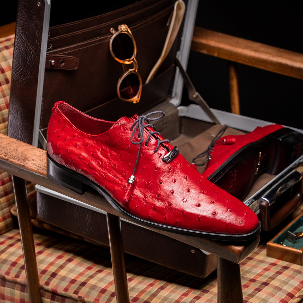 Introducing the Criss Red by Marco Di Milano: a pair of striking red genuine ostrich quill leather dress oxford shoes with black laces—one elegantly upright and the other displayed on its side to showcase the luxurious sole. This luxury footwear commands attention at every step.