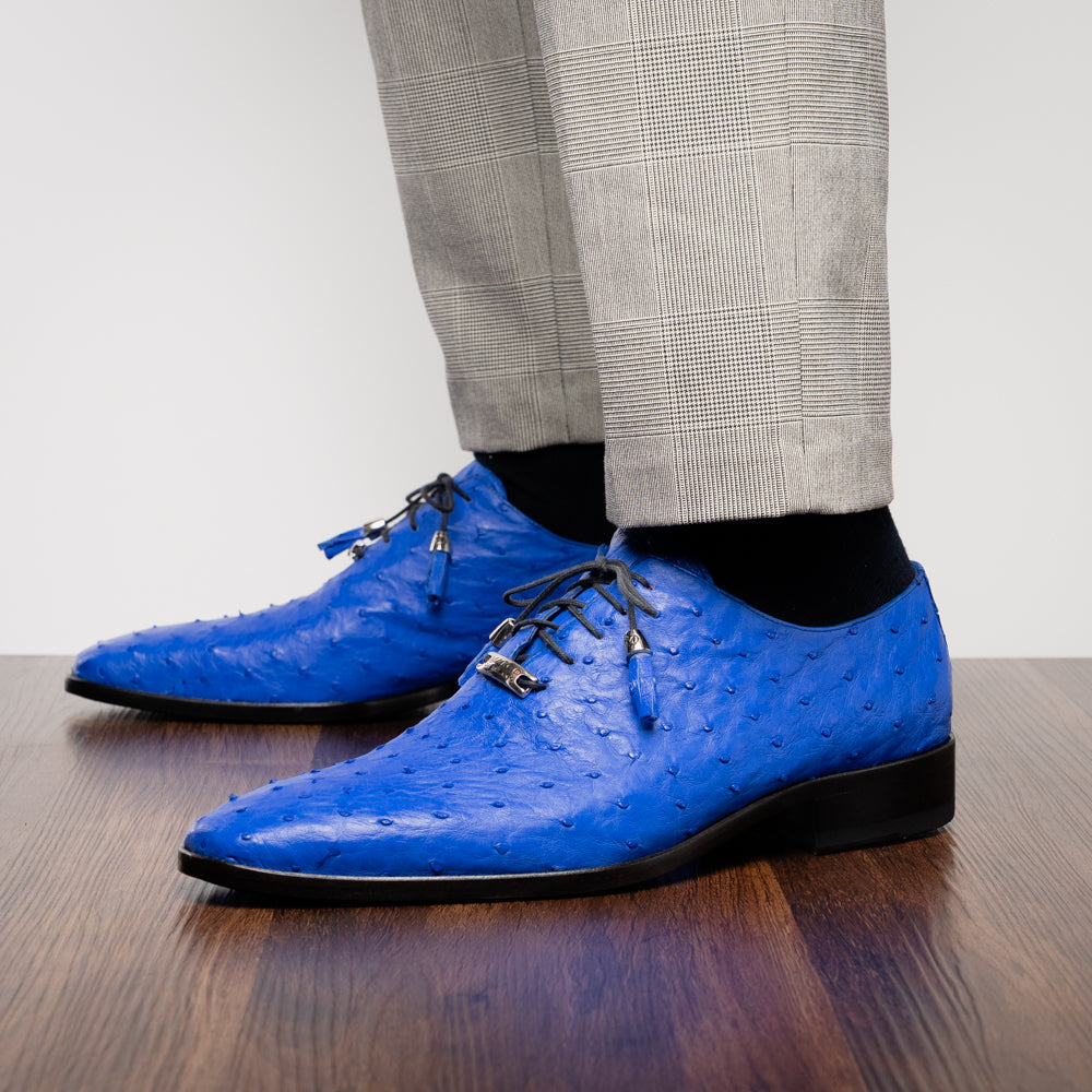 Introducing the Criss Electric Blue by Marco Di Milano—a pair of vibrant blue genuine ostrich quill leather oxford dress shoes featuring stylish laces and sleek metal detailing. One shoe stands upright while the other displays its beautifully crafted sole, making them an exceptional choice for anyone looking for distinctive luxury footwear.