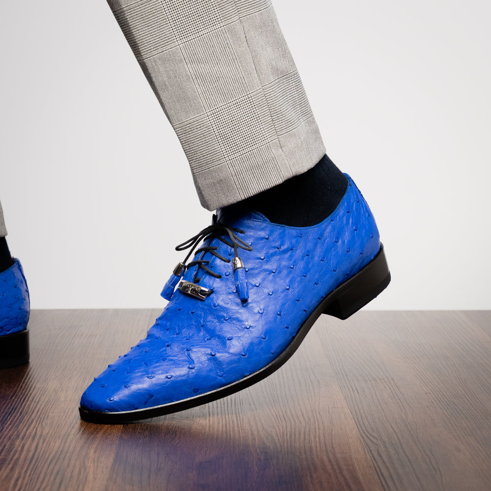 Introducing the Criss Electric Blue by Marco Di Milano—a pair of vibrant blue genuine ostrich quill leather oxford dress shoes featuring stylish laces and sleek metal detailing. One shoe stands upright while the other displays its beautifully crafted sole, making them an exceptional choice for anyone looking for distinctive luxury footwear.