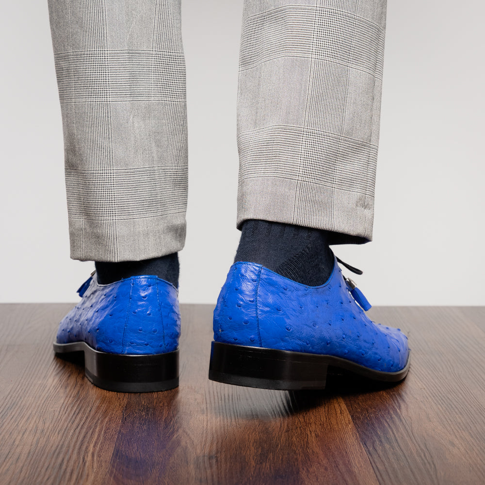 Introducing the Criss Electric Blue by Marco Di Milano—a pair of vibrant blue genuine ostrich quill leather oxford dress shoes featuring stylish laces and sleek metal detailing. One shoe stands upright while the other displays its beautifully crafted sole, making them an exceptional choice for anyone looking for distinctive luxury footwear.