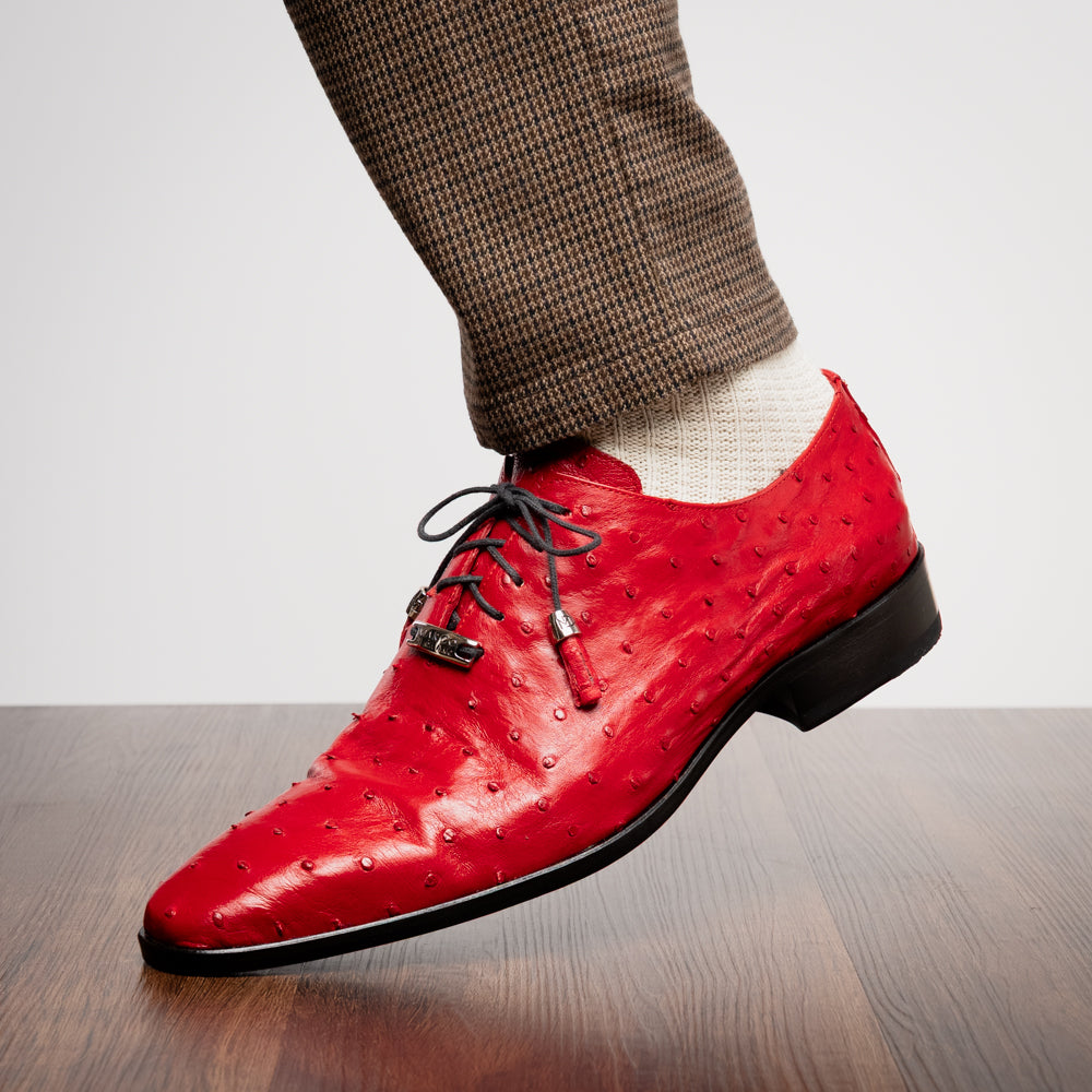 Introducing the Criss Red by Marco Di Milano: a pair of striking red genuine ostrich quill leather dress oxford shoes with black laces—one elegantly upright and the other displayed on its side to showcase the luxurious sole. This luxury footwear commands attention at every step.