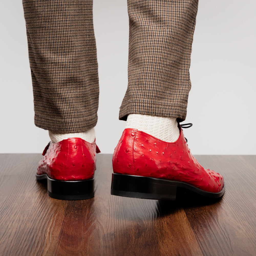 Introducing the Criss Red by Marco Di Milano: a pair of striking red genuine ostrich quill leather dress oxford shoes with black laces—one elegantly upright and the other displayed on its side to showcase the luxurious sole. This luxury footwear commands attention at every step.