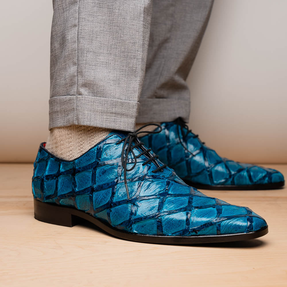 A pair of Marco Di Milano Olivieri Caribbean Blue crocodile leather oxfords with red interior lining; one shoe stands upright, the other shows its sole with "Marco Di Milano" branding.