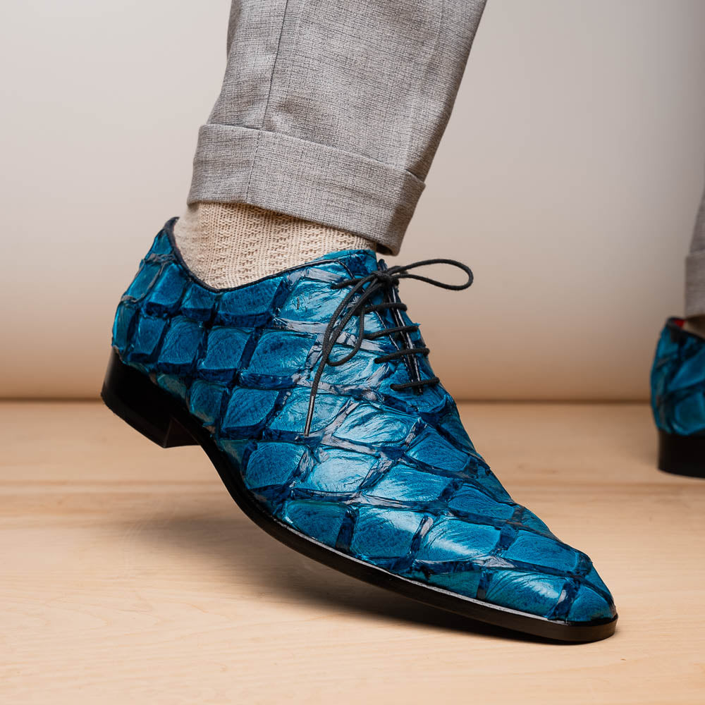 A pair of Marco Di Milano Olivieri Caribbean Blue crocodile leather oxfords with red interior lining; one shoe stands upright, the other shows its sole with "Marco Di Milano" branding.