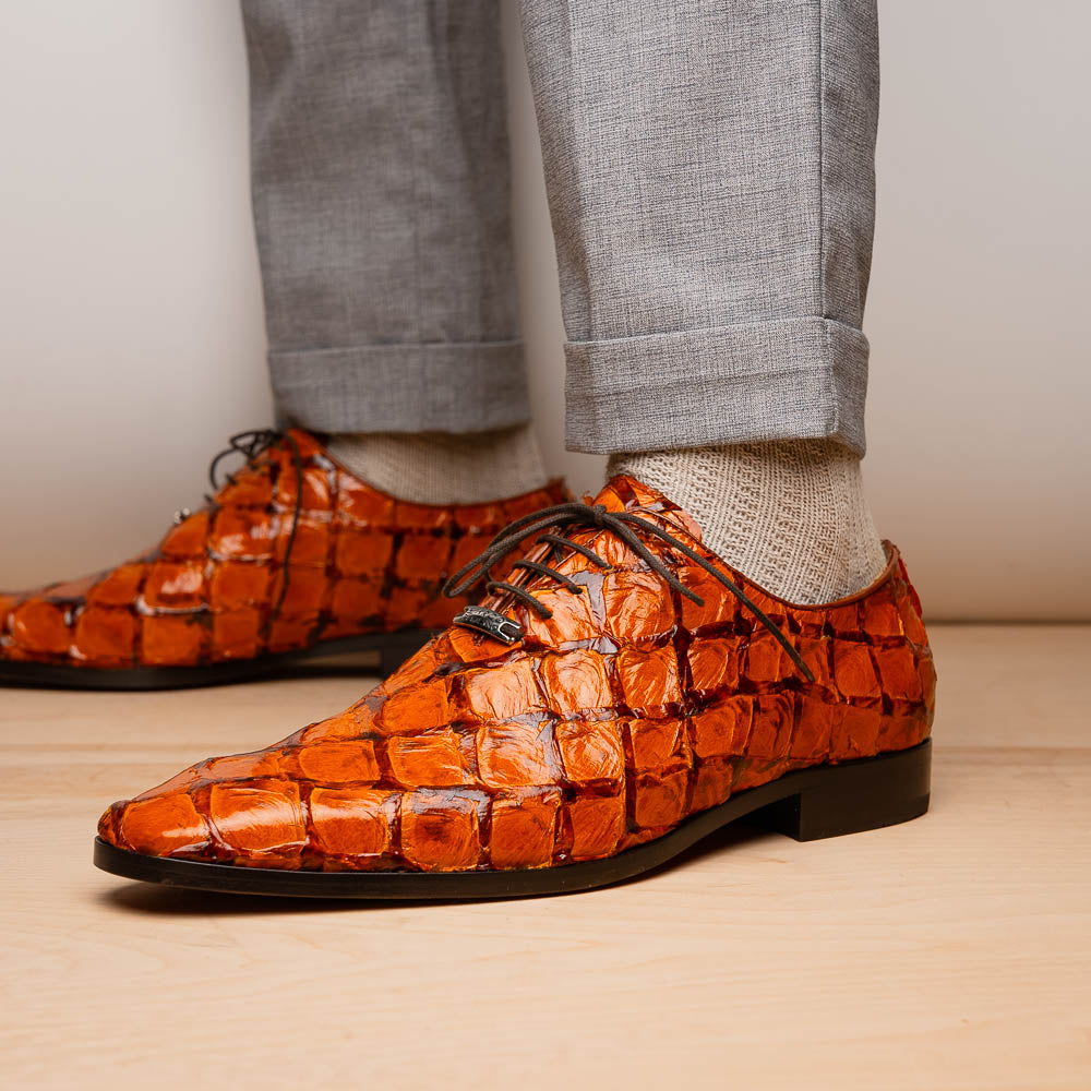 A pair of Olivieri Brandy by Marco Di Milano luxury dress oxford shoes in orange-brown crocodile leather with dark laces, one shoe shown on its side highlighting the branded sole.