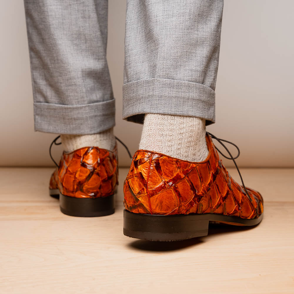 A pair of Olivieri Brandy by Marco Di Milano luxury dress oxford shoes in orange-brown crocodile leather with dark laces, one shoe shown on its side highlighting the branded sole.