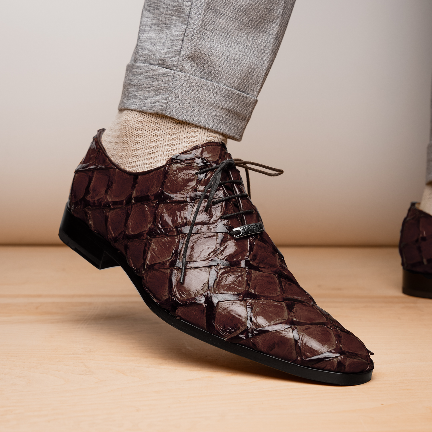 A pair of Olivieri Brown oxford shoes by Marco Di Milano—one upright, one on its side revealing the branded sole—showcase luxurious crocodile leather craftsmanship.