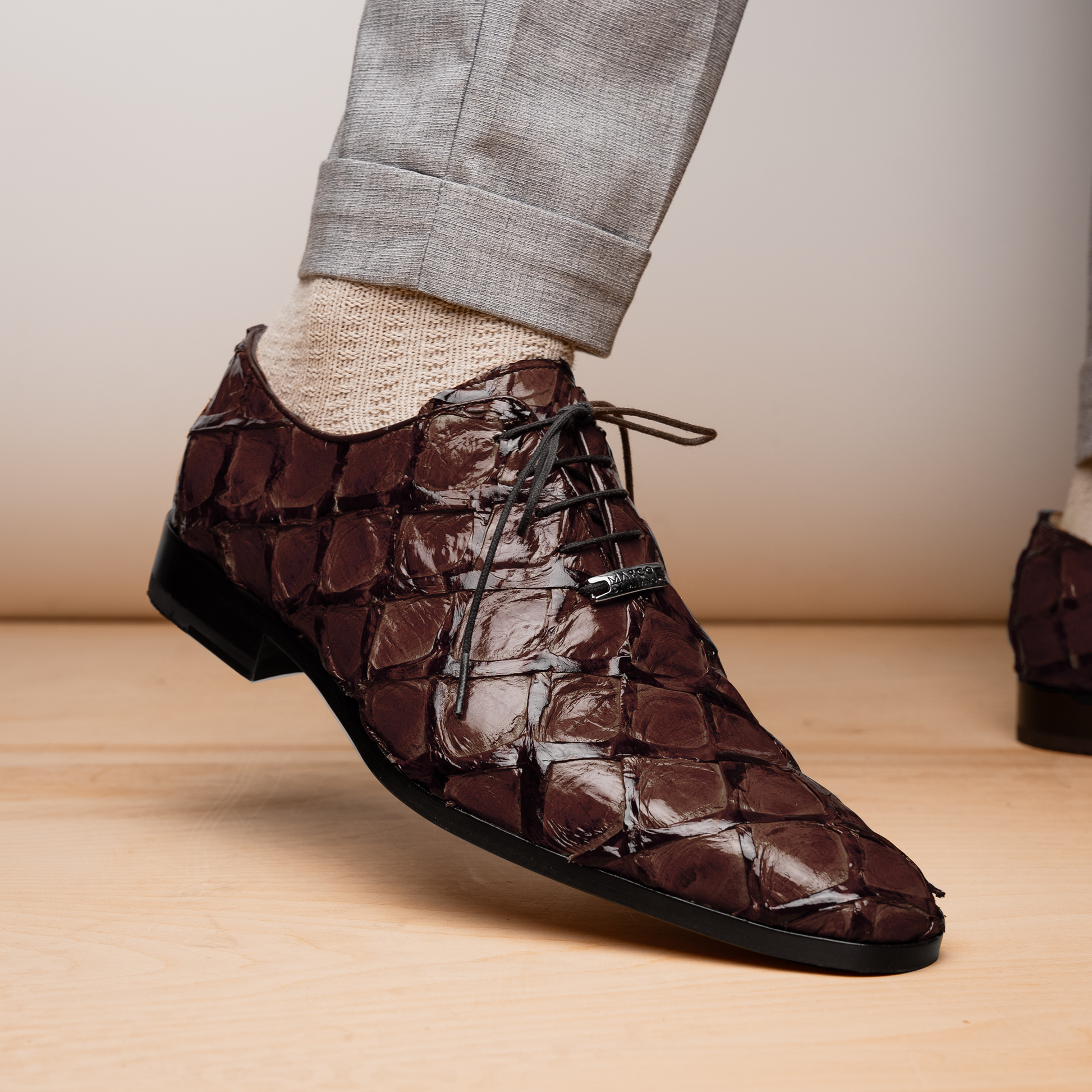 A pair of Olivieri Brown oxford shoes by Marco Di Milano—one upright, one on its side revealing the branded sole—showcase luxurious crocodile leather craftsmanship.