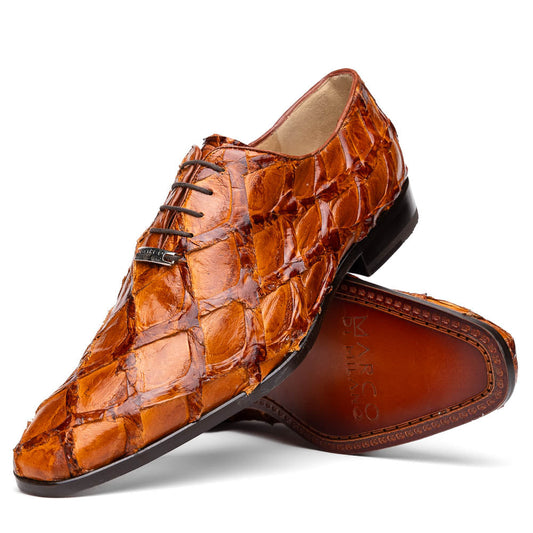 A pair of Olivieri Cognac dress shoes by Marco Di Milano, crafted from brown crocodile leather with black laces—one shoe stands upright, the other shows its sole—ideal for lovers of luxury footwear.