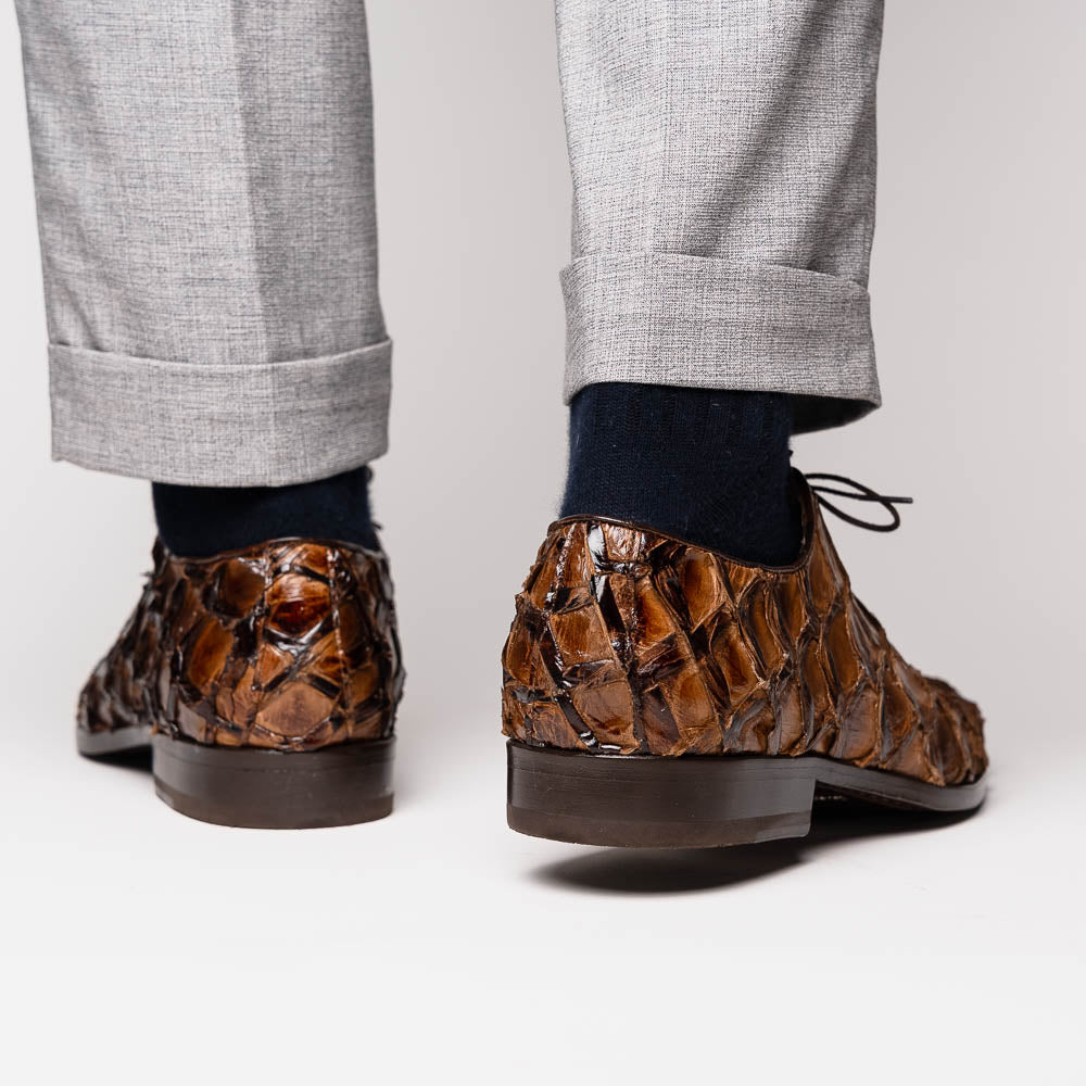 The Olivieri Clear Brown oxford shoes by Marco Di Milano showcase a textured crocodile leather design; one shoe stands upright as the other lies on its side, displaying the sole.