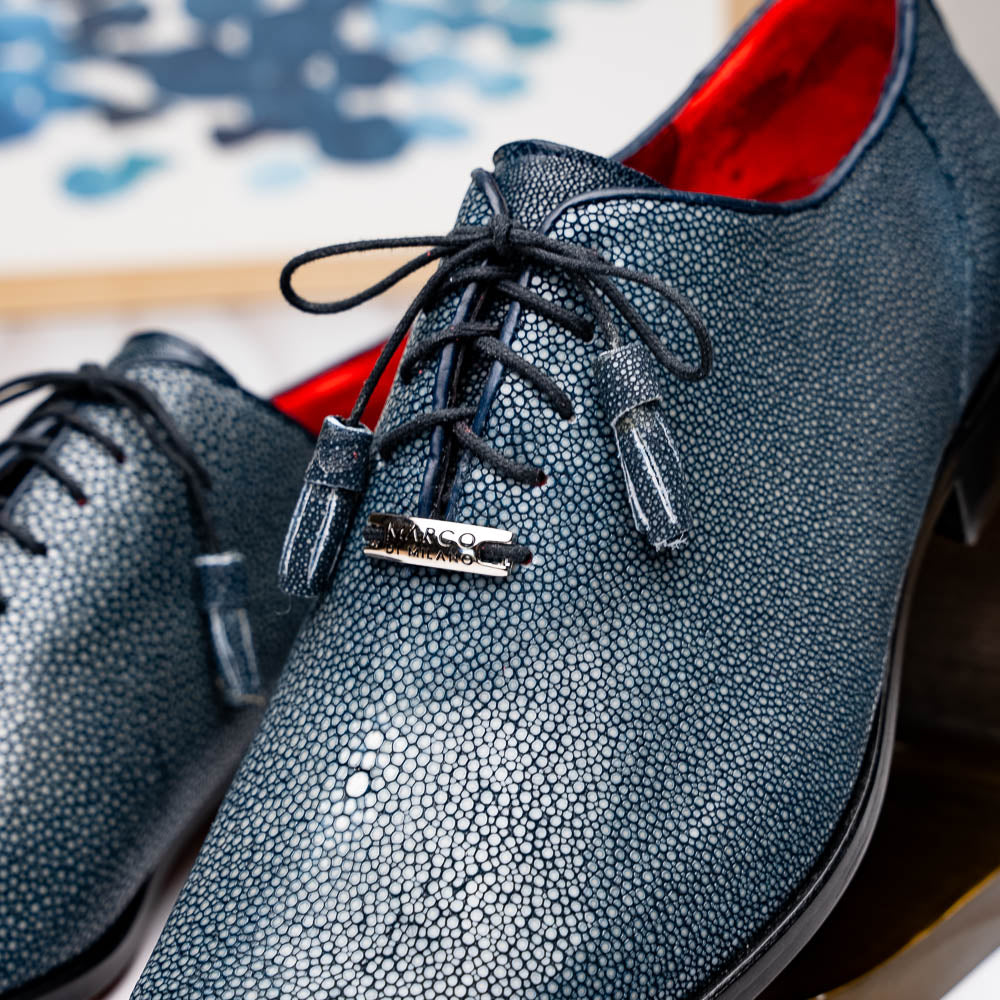 A pair of Marco Di Milano Pannuci Navy dress oxford shoes in textured dark blue leather with black laces, red inner lining, and tan soles—one displayed on its side to showcase the branded sole.