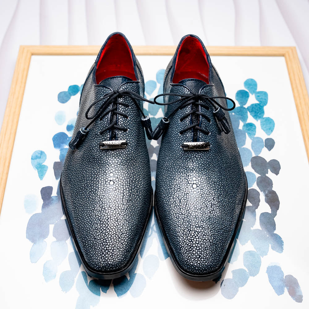 A pair of Marco Di Milano Pannuci Navy dress oxford shoes in textured dark blue leather with black laces, red inner lining, and tan soles—one displayed on its side to showcase the branded sole.
